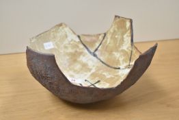 A studio pottery bowl decorated with geometrical patterns on a brown glaze and having impressed mark