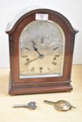 A mahogany cased arched mantel clock having silvered Roman dial with striking movement and key,