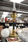 A brass Corinthian column oil lamp having glass chimney and circular shade, the body decorated