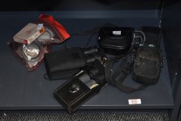 A selection of photographic lens filters, three small pairs of binoculars, and a Lumix digital