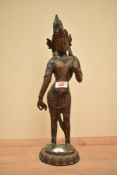 A patinated metal Thai Buddha sculpture, standing wearing traditional dress with raised hand, h41cm