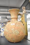 A 20th century terracotta vessel, having textured body, trumpet spout and ripple style handle,