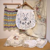 A collection of early-to-mid 20th century domestic linens, comprising two handmade pinafores, an