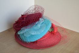 Three ladies fascinators or wedding hat / headpieces, each with a net veil, in red, burgundy and
