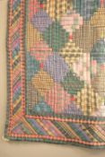 A patchwork quilt showcasing a diamond design in rich, deep shades of forest green, navy and faded