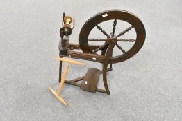 A modern stained wood spinning wheel of traditional design with foot operated treadle, spindled