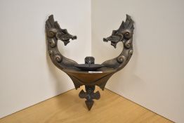 A modern cast-resin and metal wall mounted pricket candlestick, formed as two dragons holding the