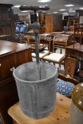 A vintage galvanised bucket and pump attachment