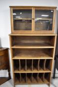 An early 20th Century oak cabinet having glazed upper section, over two open bookshelves and two