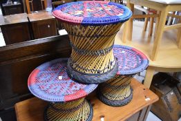A set of three ethnic art style stools or occasional tables having woolwork tops with woven frames