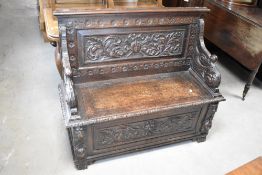 A 19th Century oak monks bench having heavily carved decoration, width approx. 108cm