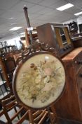 A Victorian pole screen with period tapestry insert, on turned column and triple scroll feet