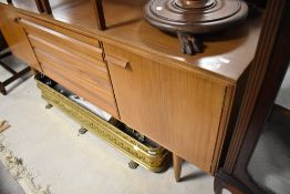 A vintage Mid Century Modern teak sideboard having four central slimline drawers, flanked by