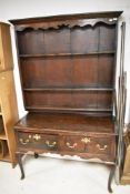 A period oak dresser in the Georgian style, with shaped apron to delft rack over two drawer base
