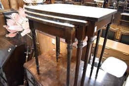 A reproduction nest of three mahogany occasional tables having glass inset tops, width approx. 54cm