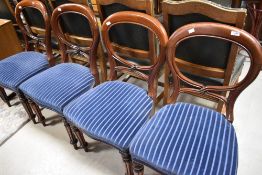 A set of four Victorian mahogany balloon back chairs having later blue stripe upholstery