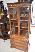 A reproduction bookcase in the period style having brushing slide and four drawers to base, width