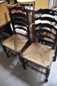 A pair of 19th Century elm or ash dining chairs having shaped ladder backs and rush seats