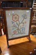 A traditionally mahogany fire screen having embroidered panel