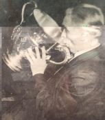 Artist unknown, black and white photograph of a man lifting a trophy to drink from it, caption - '