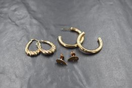 Three pairs of 9ct gold and yellow metal earrings, comprising a pair of 9ct gold twist hoop
