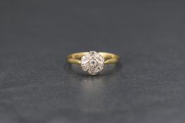 An Edwardian 18ct gold diamond daisy cluster ring, the central diamond with a six diamond chip