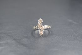 A white metal diamond set vertical twist ring stamped 18K having several pave set diamond chips to