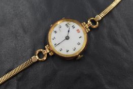 A lady's vintage 9ct gold wrist watch having an Arabic numeral dial on a white enamelled face (