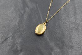A small 9ct gold oval locket having an engraved border, with a fine 9ct gold rope chain, marked 9ct,