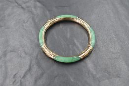 A Chinese jade and yellow metal hinged bangle having engraved decoration, and concealed clasp,