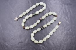 A string of Chinese oval jadeite beads interspersed by five cloisonné decorative beads and having an