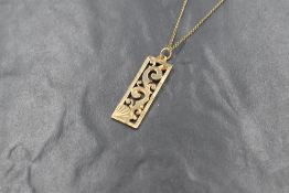 A 9ct gold pendant and chain having cut out scroll decoration, marked 375 and the chain being