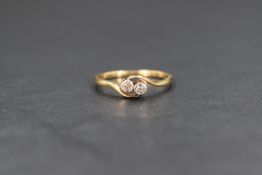 A yellow metal two stone diamond cross over ring, the two small diamonds each measuring