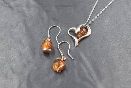 A pair of silver and amber drop earrings, the circular amber cabochons in a wrap around setting on