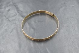 A 9ct gold expanding bangle, having decorative scroll engraving, marked 375, 7.8g