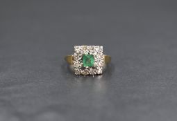 An 18ct gold emerald and diamond cluster ring, the central emerald cut emerald measuring
