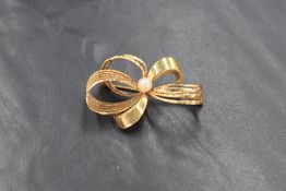 A 9ct gold ribbon bow brooch, the alternating smooth and textured ribbons set with a central