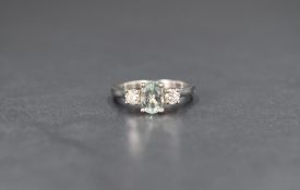 A platinum tourmaline and diamond set ring having a central mint coloured oval tourmaline flanked by