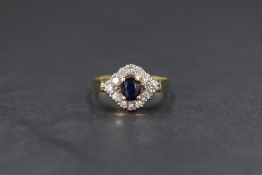 An 18ct gold sapphire and diamond cluster ring, the central oval cut blue sapphire in an illusion
