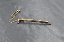 A yellow metal bar brooch stamped 9ct modelled as a riding crop, metal pin, approximately 1.7g