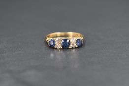 An 18ct gold sapphire and diamond set ring, the three graduated old cut blue sapphires measuring