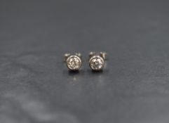 A pair of white metal diamond solitaire stud earrings, each brilliant cut diamond being
