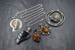 Five polished stone and fossil silver mounted pendants including Baltic amber, ammonite etc, with