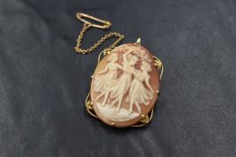 A conch shell cameo brooch/pendant depicting the three graces in a delicate claw set yellow metal