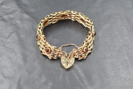 A 9ct gold fancy link bar bracelet having garnet cabochon decoration and a padlock clasp, marked