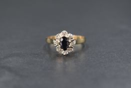 A 9ct gold sapphire set cluster ring, the central oval cut blue sapphire in an illusion set
