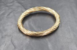 A 9ct gold hinged bangle, of twisted form with safety clip marked 375, approximately 6cm internal