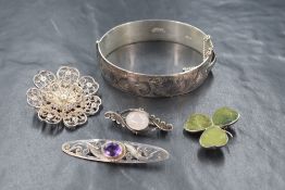 A hinged silver bangle by Excalibur having engraved scroll decoration and four silver and white