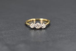 An 18ct gold diamond set trilogy ring having three old cut diamonds in claw set mounts, total