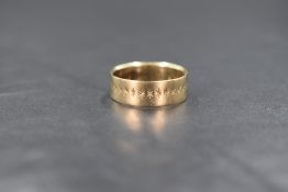 A 9ct gold band, having star burst engraving, marked 375, ring size M, 2.5g